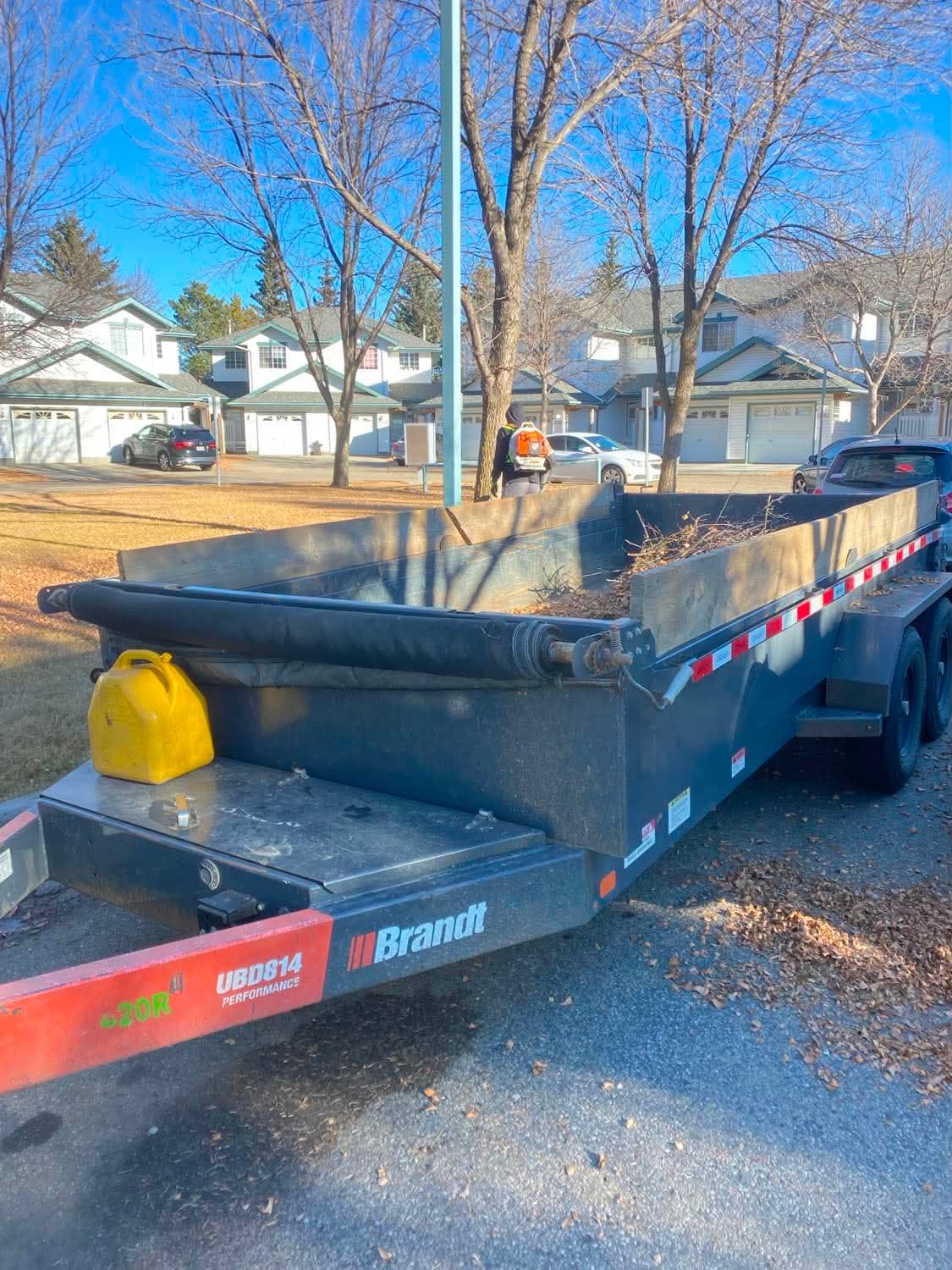 A dump trailer loaded with leaves and yard debris during a fall cleanup at a townhouse complex