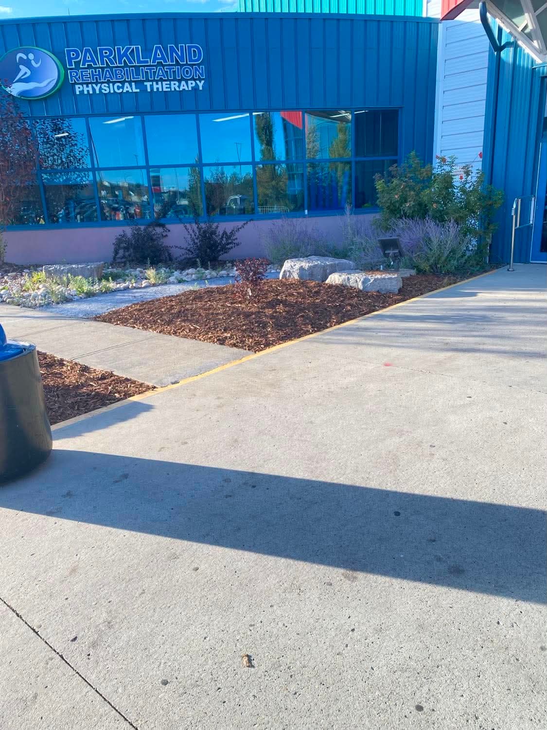 A commercial clinic entrance fronted by a freshly mulched bed with new shrub planting